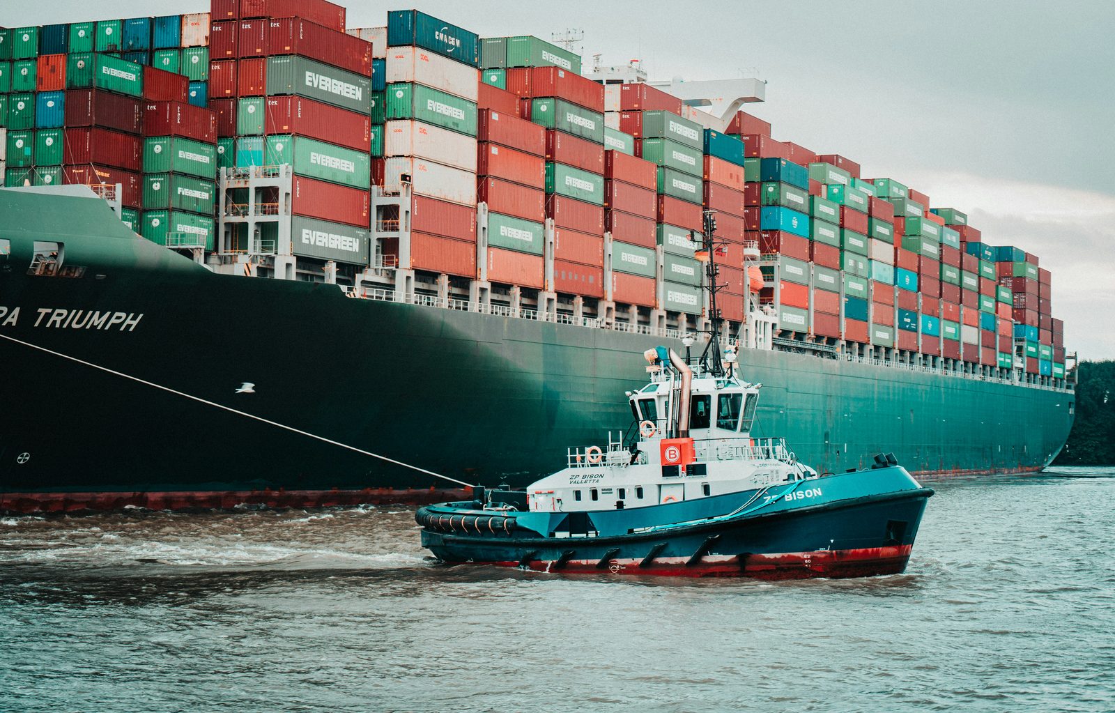 A tugboat guiding a large container ship safely into port